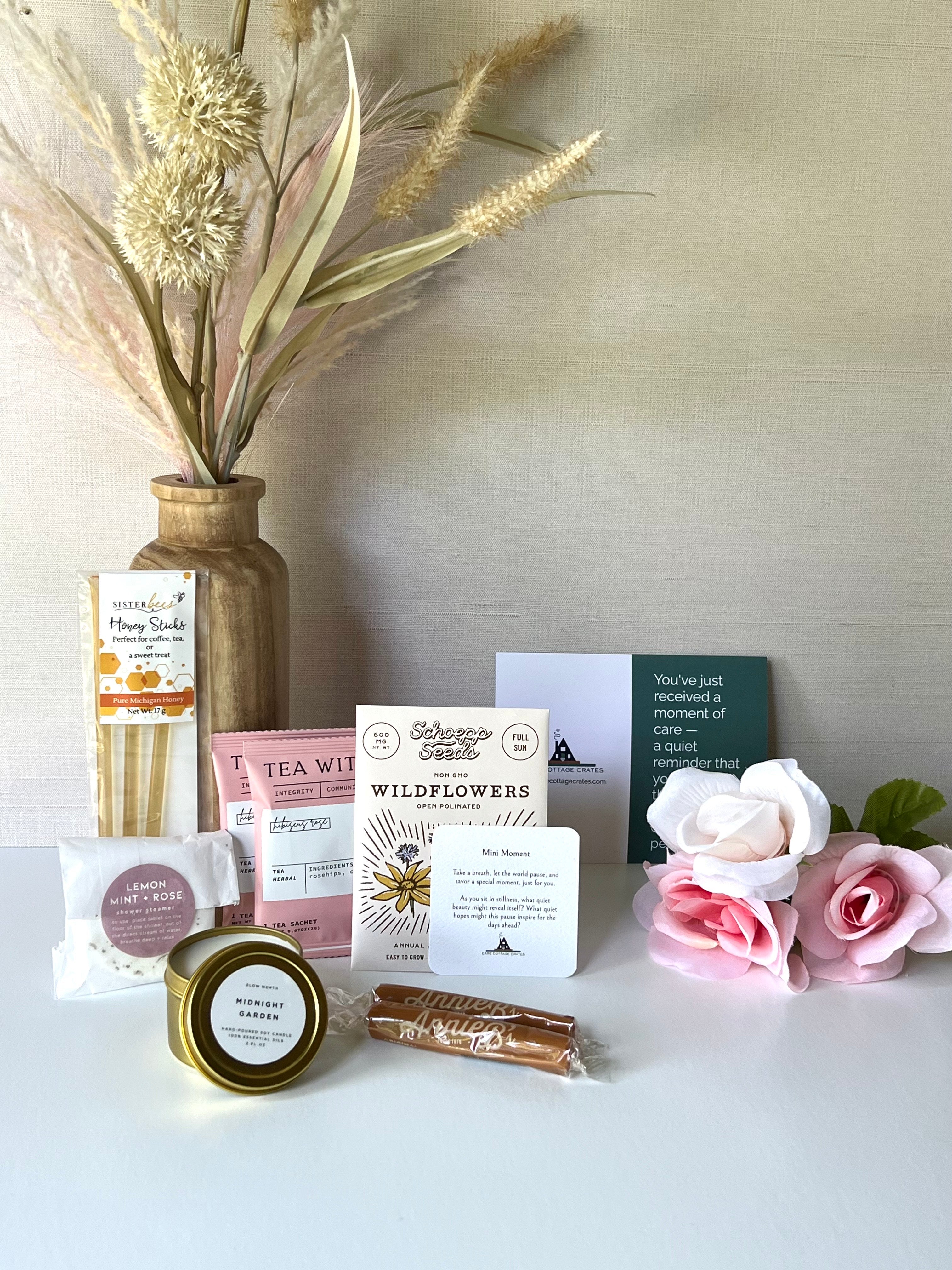 Honey sticks, rose hibiscus tea, shower steamer, mini candle, wildflower seed packet, and caramels make for a great gift. Includes a thoughtful prompt and a curated playlist to encourage a moment of peace.