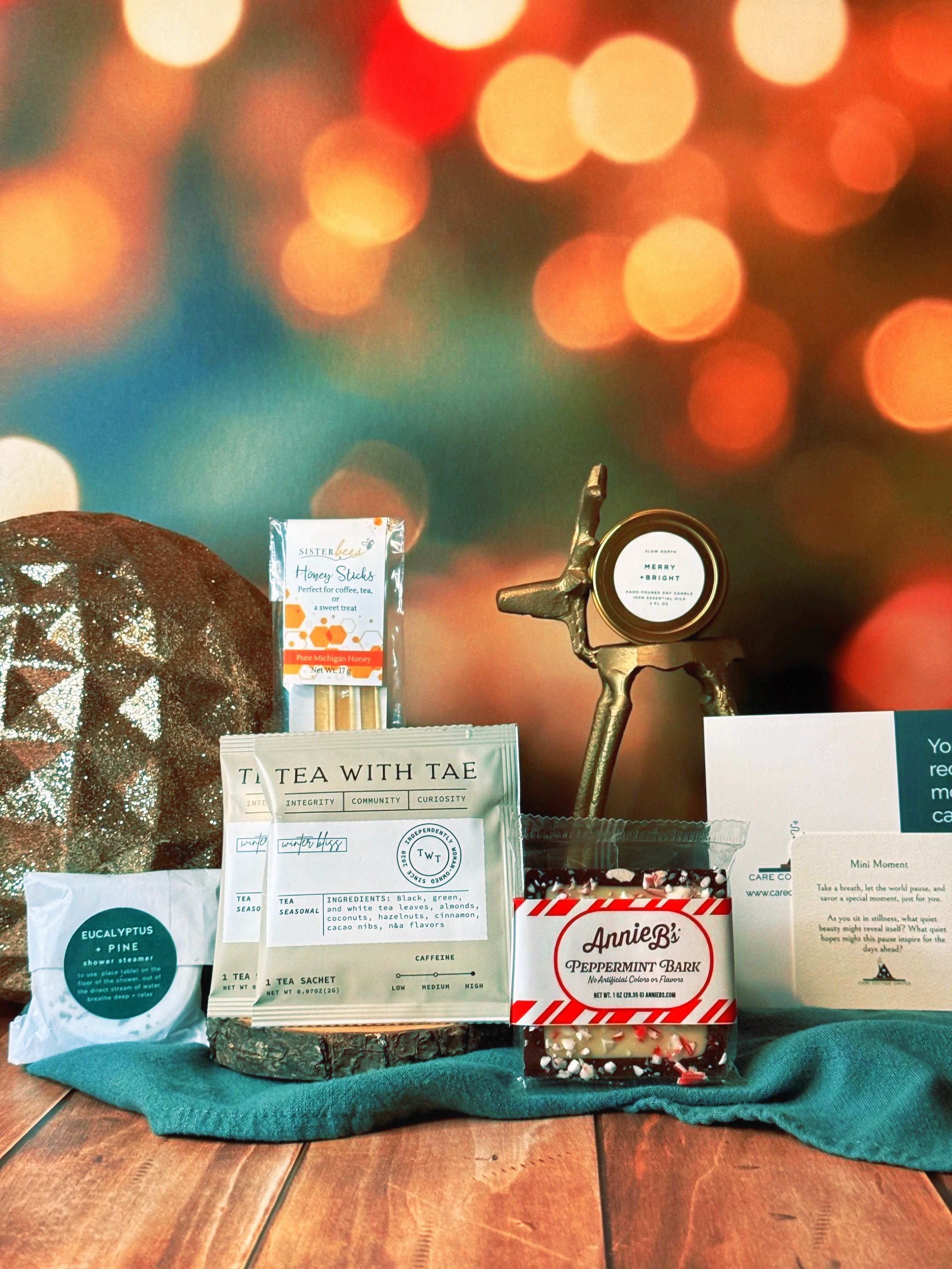A great gift for teachers, friends, sisters, etc. Our Mini Merry Moment includes a thoughtful prompt card, customized playlist, and a plethora of products from small makers. Inside you'll find: Eucalyptus and Pine Shower Steamer, Tea with Tae Winter Bliss Tea, Sister Bees Honey Sticks, Slow North Merry and Bright Mini Candle, Annie B's Peppermint Bark.