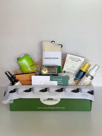 Image of Gift Basket with Forest Bathing Linen Spray, Wood Phone Charger, Recess Lime Citrus Drink, American Trench Socks, Swanky Badger Lumber Soap, Double Chocolate Chip Cookies, Oars + Alps Sunscreen and Into the Wild Natural Bug Spray.