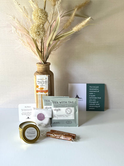 Shower Steamer, Calming Tea Packes, Honey Sticks, Caramels, and mini candle make for a thoughtful gift. Includes a thoughtful prompt and a custom playlist for a moment of peace. 