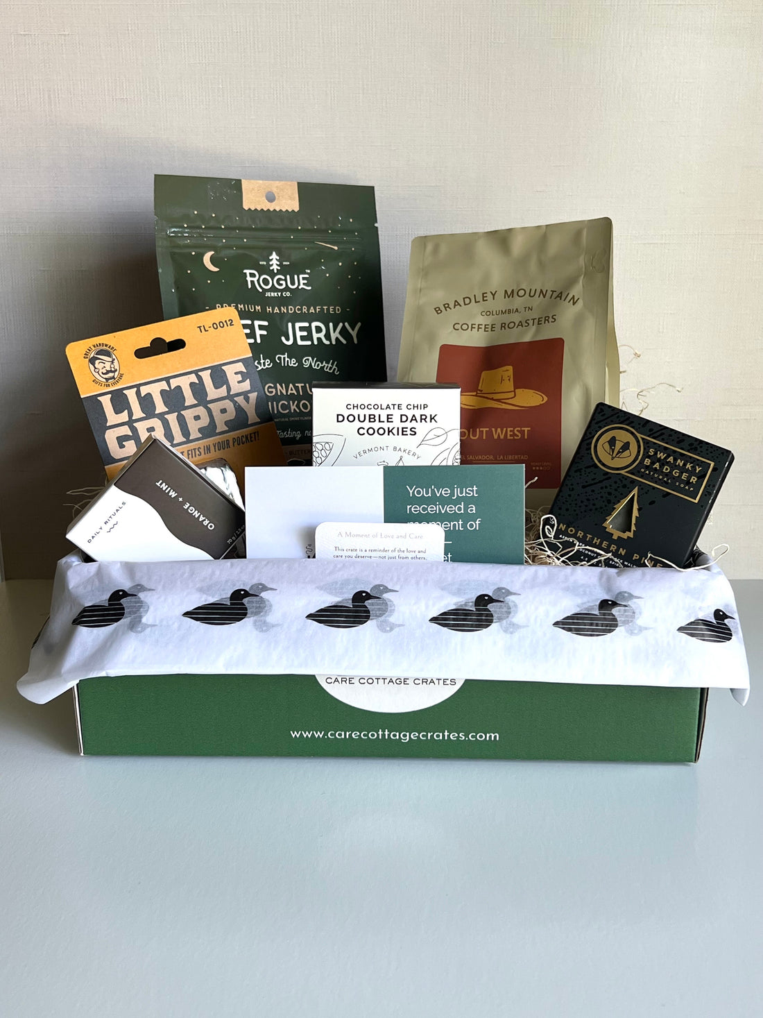 Beef Jerky, Bradley Mountain Coffee, Little Grippy Tool, Shower Steamer, Double Chocolate Chip Cookies, Swanky Badger Pine Soap. Includes a thoughtful prompt and curated playlist encouraging peace.